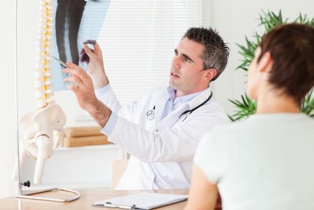 ο γιατρός δείχνει τη βλάβη στη σπονδυλική στήλη λόγω της αυχενικής οστεοχόνδρωσης